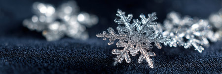 Delicate snowflakes rest on a textured dark fabric, showing their unique patterns and sparkling details in the cold winter season.の素材