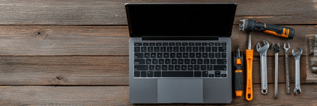 A laptop sits on a rustic wooden table surrounded by various hand tools, highlighting a workspace dedicated to technical repairs and maintenance.の素材