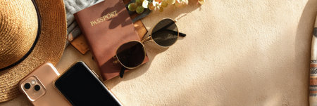 Sunglasses, a passport, and a smartphone are arranged on a warm sandy surface, reflecting a relaxed summer vibe and readiness for exploration.の素材
