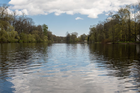 Calm waters reflect the greenery of trees surrounding the lake, creating a serene atmosphere in a...