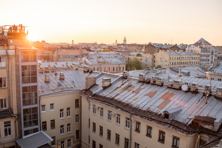 Golden sunlight illuminates the rooftops of St Petersburg as day transitions to night, highlighting the citys historical buildings and tranquil atmosphere.の写真素材