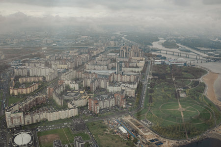 Residential buildings and green spaces in St. Petersburg are visible from above, with a river winding through the city under cloudy skies.の写真素材