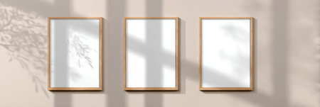 Three empty wooden frames hang on a beige wall, softly illuminated by natural light, with shadows creating a tranquil ambiance in the room.の素材