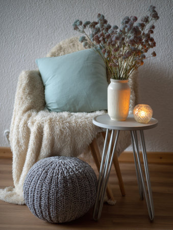 A comfortable chair adorned with a fluffy throw and a soft pillow holds a decorative vase of dried flowers and a glowing candle, enhancing the rooms warmth.の素材