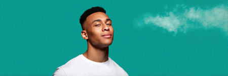 A young man exudes confidence against a turquoise backdrop, calmly engaging with the camera in the afternoon.の素材