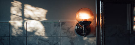 Soft light from a decorative wall lamp casts shadows on marble tiles, creating a cozy atmosphere in the bathroom late in the afternoon.の素材