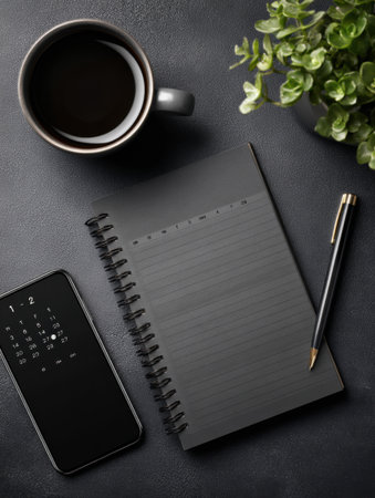 A cup of coffee sits next to a blank notebook and a smartphone displaying a calendar. A pen lies ready for notes, creating a focused workspace ambiance.の素材