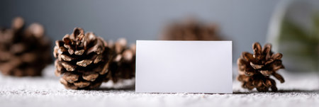 Blank card placed among rustic pine cones on a textured surface creates an aesthetic display suitable for winter decor or artistic projects.の素材