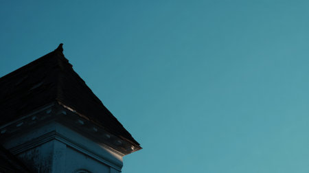 The dark outline of a roof contrasts with a bright blue sky during twilight, emphasizing the architectural details of the historic structure.の素材