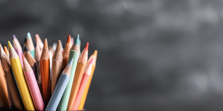Various colored pencils are neatly positioned in a holder against a blurred dark background, ideal for drawing and crafting activities.の素材