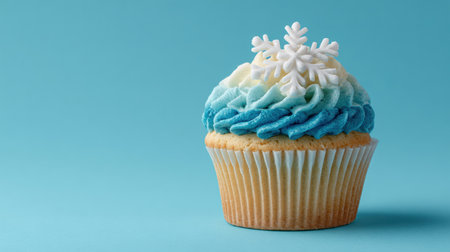Delightful cupcake features swirls of blue and white icing topped with a decorative snowflake on a bright blue background, ready for a celebration.の素材