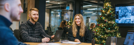 Colleagues engage in a brainstorming session in a festive office setting, featuring a Christmas tree and holiday decorations, promoting teamwork and creativity.の素材