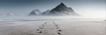 Snowy footprints stretch across a tranquil, icy expanse, guiding the gaze toward stunning mountains enveloped in a soft mist, creating a peaceful ambiance.の素材