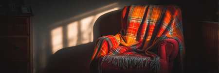 A comfortable armchair is draped with a vibrant plaid blanket, basking in gentle afternoon sunlight that creates warm shadows across the room.の素材