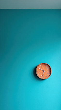 This modern wall clock features an orange face and contrasting hands, mounted on a bright teal wall in a stylish interior environment.の素材