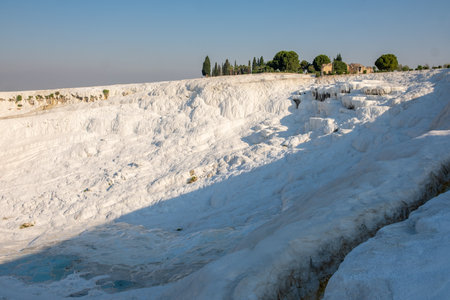 Experience the breathtaking beauty of Pamukkales white terraces formed by mineral deposits, with serene blue water pools complementing the landscape.の写真素材