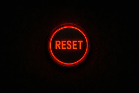 The vibrant red reset button illuminates in a dark setting, signaling users to restart an electronic device or system whenever needed.の素材