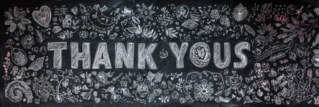 A chalkboard wall showcases creative doodles with a central message of thanks, highlighting gratitude in a playful and artistic manner.の素材