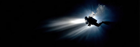 Diver explores the deep ocean, utilizing a bright light to reveal hidden marine life and stunning underwater landscapes in complete darkness.の素材