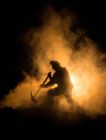 A silhouetted miner is seen in the dark, working with a pickaxe. He is wearing a helmet, and the area is filled with smoke, illuminated by a light source.の素材
