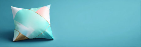 A decorative pillow featuring geometric designs in pastel colors is placed on a smooth blue surface, adding a vibrant touch to the decor.の素材