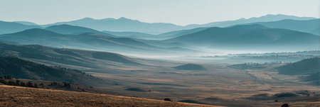 Early morning fog envelops the vast valley as distant mountains rise under a tranquil sky, creating a serene and peaceful atmosphere in nature.の素材