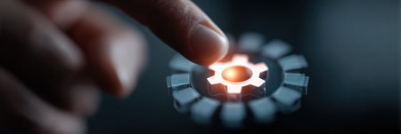 A finger gently presses a glowing gear symbol on a digital interface, highlighting an innovative technology element in a low-light environment.の素材