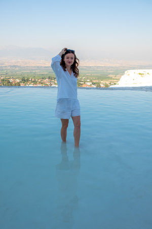 A woman wades in the turquoise waters of Pamukkales travertine pools while enjoying the beautiful scenery and tranquility of this natural wonder.の写真素材