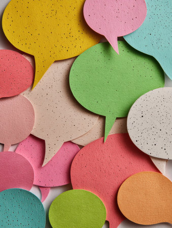 Assorted colorful speech bubbles made from textured materials spread across a white surface, illustrating vibrant conversation and creativity.の素材