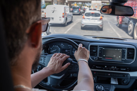 A driver maneuvers through heavy traffic in a bustling city, focusing on the road ahead while...