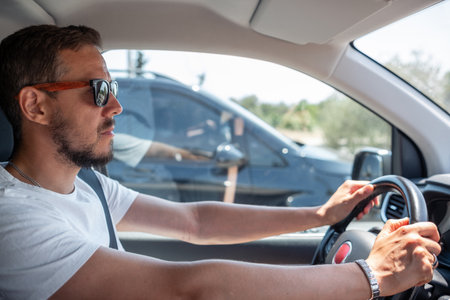 Driving Through a Bustling City Street During a Sunny Day, a Man Focuses on the Road Ahead While...