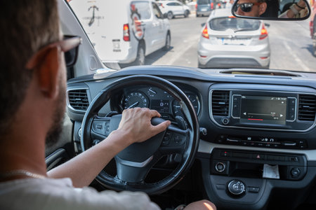 Driving Through City Traffic on a Sunny Day With Focus on the Steering Wheel and Dashboard Controlsの写真素材