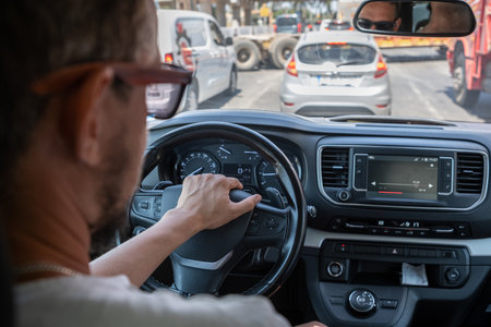 Busy City Traffic Observed From Inside a Vehicle With a Focus on a Driver Navigating Through...