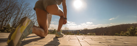 Athlete getting ready for a morning run on a sunny day, showcasing determination and an open landscape under a bright sky.の素材
