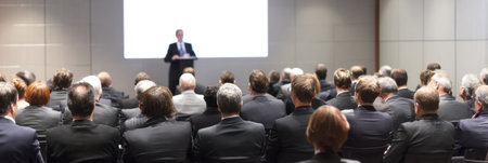 Professionals attentively watch a speaker at a corporate event held in a sleek, modern conference room during a daytime session.の素材