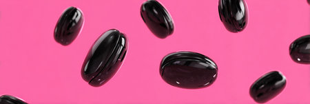 Black jelly beans appear to float in mid-air against a bold pink backdrop, creating an engaging and colorful display that captures attention.の素材