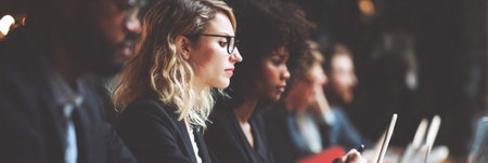 A team of professionals, including men and women of varied backgrounds, engaging with laptops in a collaborative environment.の素材