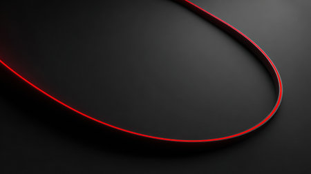A smooth red line flows across the dark surface, drawing attention with its vibrant color and dynamic shape, emphasizing the interplay of light and shadow.の素材