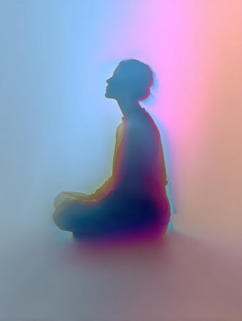 A person sits in a cross-legged position, enveloped in soft hues of color, creating a calming and peaceful ambiance in the space.の素材