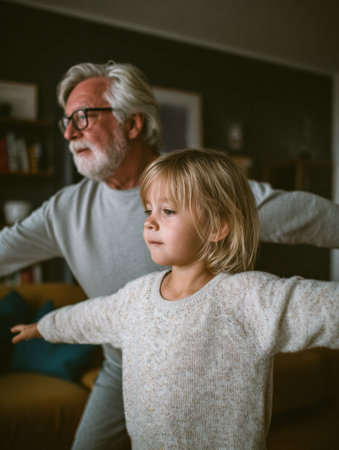 An elderly man and a young girl joyfully stretch their arms in a cozy living room, sharing a playful bond together.の素材