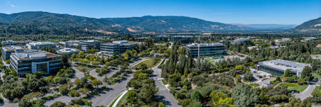 A tech campus nestled in lush greenery and rolling hills features modern architecture and vibrant landscaping by a serene valley.の素材