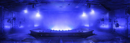 A vast industrial environment is bathed in a cool blue light, creating a mysterious ambiance amidst a swirling mist.の素材