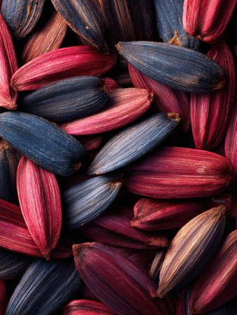 A detailed view of various seed pods displaying rich colors of deep blue, crimson, and lavender tones against a dark background.の素材