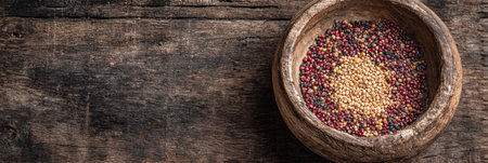 A rustic wooden bowl displays a vibrant mix of grains and seeds, showing their natural colors against a dark, textured background.の素材
