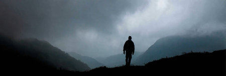 A figure stands on a hillside, surrounded by dark clouds and misty hills, creating an atmosphere of solitude and contemplation as evening approaches.の素材