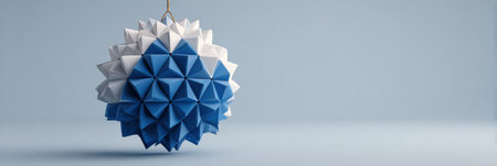 A striking ornament features a unique design with blue and white geometric shapes, suspended from a string in front of a soft blue backdrop.の素材