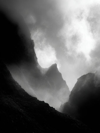 Dark mountains rise majestically from swirling fog, creating an ethereal atmosphere in the early morning light. Natures beauty is dramatic and captivating.の素材