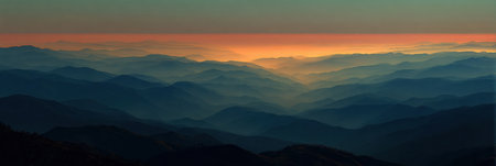 A breathtaking view of layered mountains under a colorful sunset sky, with mist enveloping the hills and creating a serene, peaceful scene.の素材