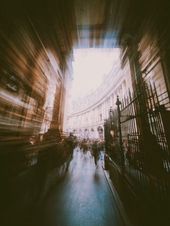 Crowds bustle through a historic archway, capturing the dynamic life of a busy street in an urban setting, enhanced by a sense of motion and light.の素材
