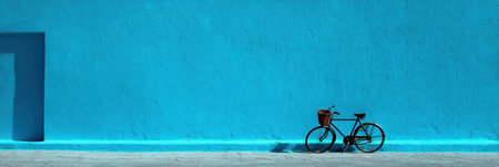 A classic bicycle stands still beside a bright blue wall, casting a gentle shadow on the ground, showcasing a peaceful moment in an urban landscape.の素材